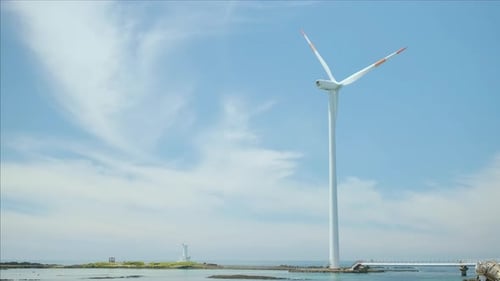 Blue sky and sea and wind turbine. Green energy and environment.