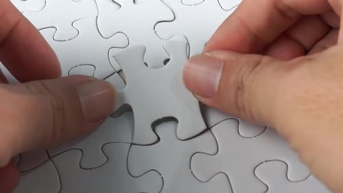 Male hand put the last white jigsaw puzzle.
