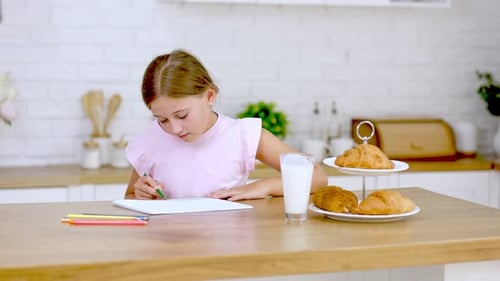 Girl Drawing and Drinking Milk in Kitchen