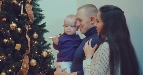Family Decorating Christmas Tree with Adorable Infant
