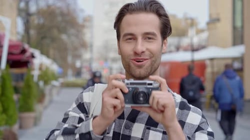 Smiling Man Taking Picture with Vintage Camera on Street