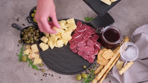 Faire un plateau d'antipasto à la viande et au fromage Femme mettant des morceaux de fromage à pâte dure au parmesan sur pierre