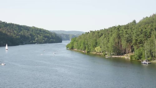A Lake Surrounded By Nature and Forests, Boats Float on the Lake, People Swim and Enjoy Water