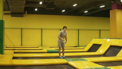 Young Man Trampolining and Flipping in Indoor Gym