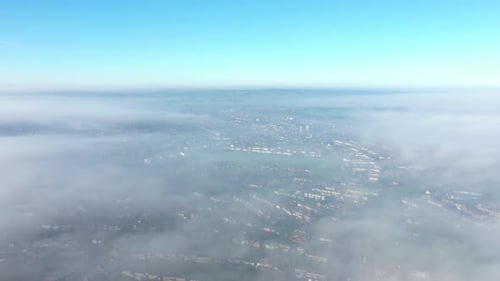 Aerial view of a city covered by fog and clouds