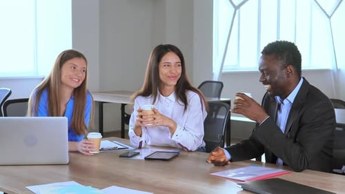 Smiling Colleagues Enjoying Coffee at a Workplace Meeting