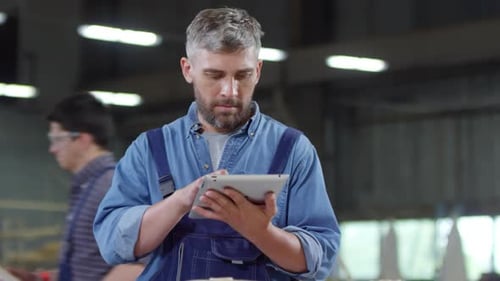 Bearded Man Uses Tablet in Woodshop