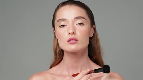 Beautiful Woman Applying Makeup with a Brush