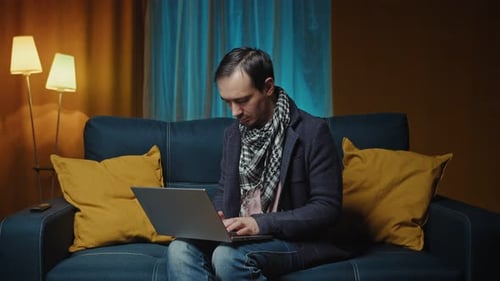 Man Using Laptop on Sofa at Home