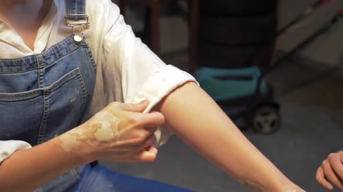 Woman Wraps Sleeves Before Work in Workshop