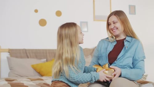 Child Gives Mother Birthday Gift on Bed