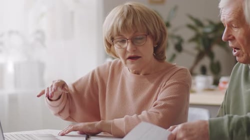 Mature Couple Discuss Documents at Home at Table