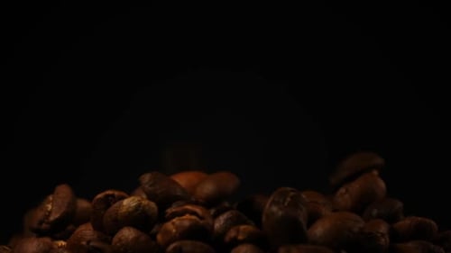 Slow motion of roasted coffee beans falling.
