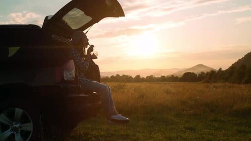 Woman Relaxing in Car Trunk at Sunset