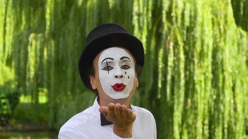 Mime on the Park zeigt Pantomime. Pantomime in einem schwarzen Hut bläst Küsse