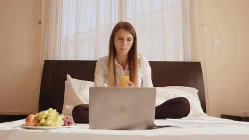 Woman Works on Laptop, Eats Fruit, Drinks Juice