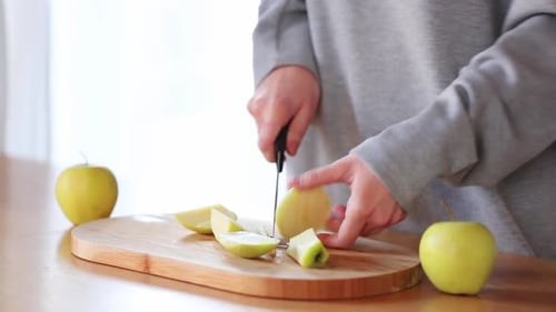 Woman Cutting Green Apples on Wooden Board