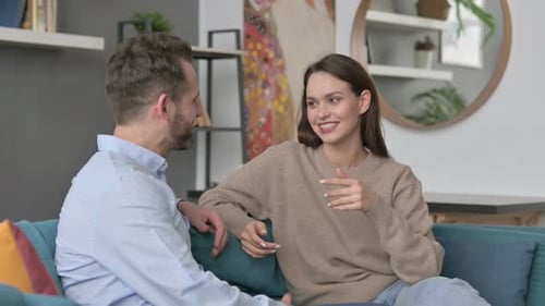 Glückliches Paar unterhält sich beim Sitzen auf dem Sofa