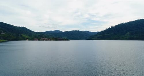 Aerial view from drone flying over water surface of tropical lake surrounded by green mountains