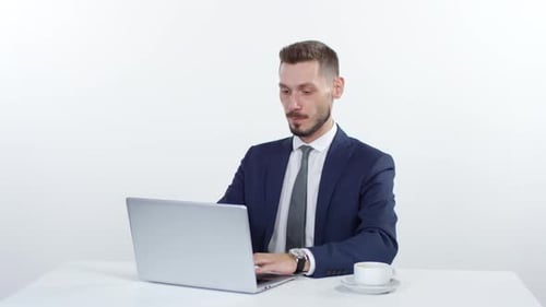 Man Working on Laptop and Drinking Coffee