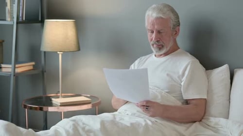 Senior Man Reading Good News in Bed