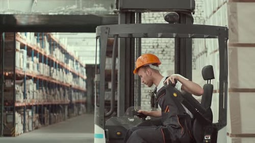 Young Worker in Uniform i Sitting in a Forklift Car