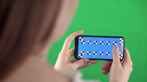 Woman Holds a Smartphone in Horizontal Orientation with Tracking Markers on Display and Swiping Left