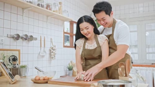Asian couple spend time together in kitchen enjoy kneaded yeast dough with hand to bake bakery.