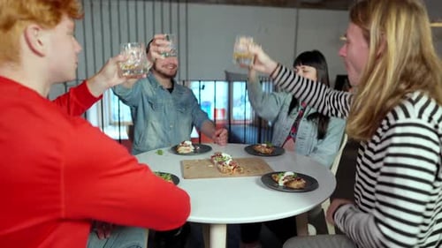Relaxed Happy Millennial Friends Clinking Glasses Drinking Whiskey and Eating Pizza in Restaurant
