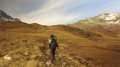 Woman Hiker Walking on Fall Fields Path to Snowy Mounts
