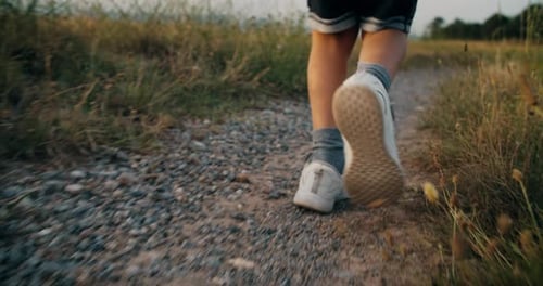 Unbeschwerter Kinderjungenlauf auf der Landstraße bei Sonnenuntergang in den Sommerferien