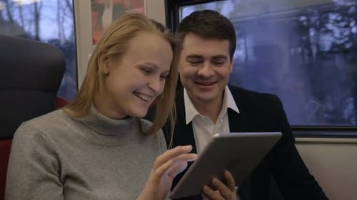Smiling Couple Using Tablet on a Train