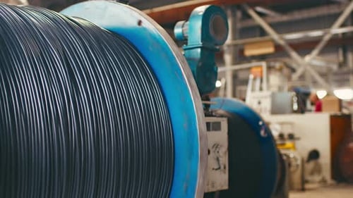 Primer plano de una bobina giratoria con cable en una planta de producción de cables