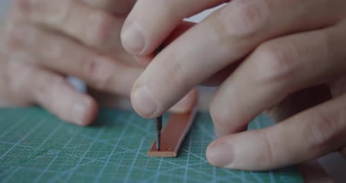 Punching Holes in a Leather Strip Part for Belt with Hole Punch Tool and Mallet