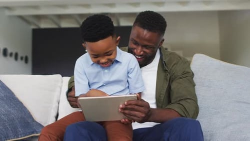 Father and Child Smiling at Tablet Together Indoors
