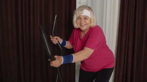 Senior Woman Exercising on Elliptical Machine at Home