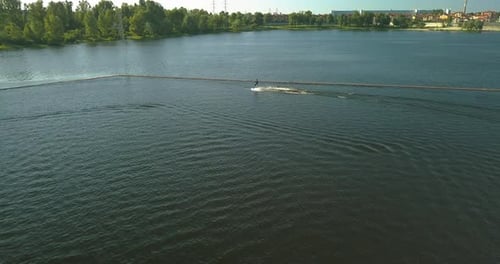 Luftaufnahme des Ankerplatzes der Seilbahn Wake Park und eines Athleten, der durch das Wasser schneidet