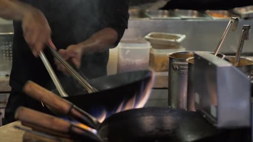 Chef Cooking Noodles in Fiery Wok in Kitchen