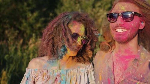 Joyful Asian Woman Hugging Happy Couple Covered with Paint Powder Smiling at Holi Festival