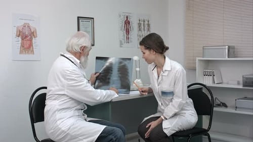 Male Doctor Explaining Lungs X-ray To Female Doctor in the Medical Office