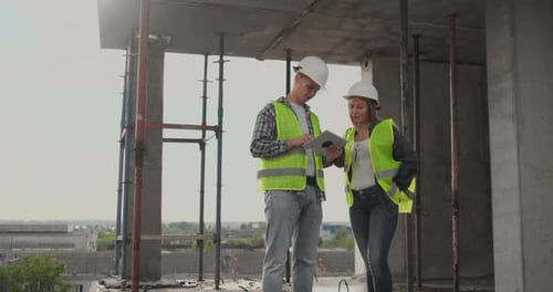 Baustellenteam oder Architekt und Baumeister oder Arbeiter mit Helmen diskutieren auf einem Gerüst