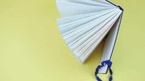 An Open Notebook with Top View on a Yellow Background
