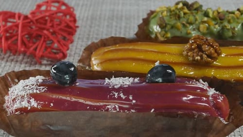 Gâteaux à la crème aux trois éclairs rouges, jaunes et verts avec pistache, cerise, banane et fruit de la passion