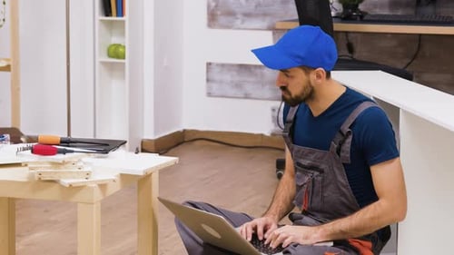 Man Assembling Furniture With Laptop Instructions Indoors