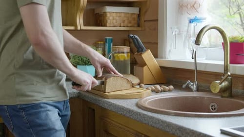 Adult Slicing Bread in Cozy Kitchen