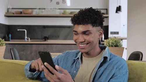 Smiling Young Adult Using Mobile Phone At Home