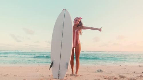 Young Energetic Caucasian Woman in Swimsuit Holding Surfboard on Beach