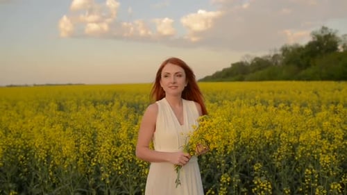 Young Redhaired Woman with Flying Hair in the Midst of a Flowering Field