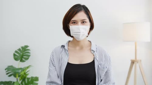 Asia businesswoman social distancing in situation for virus prevention smiling under mask in office.