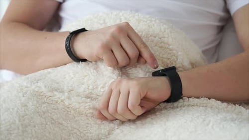 Man Using a Smart Watch While Lying in Bed
